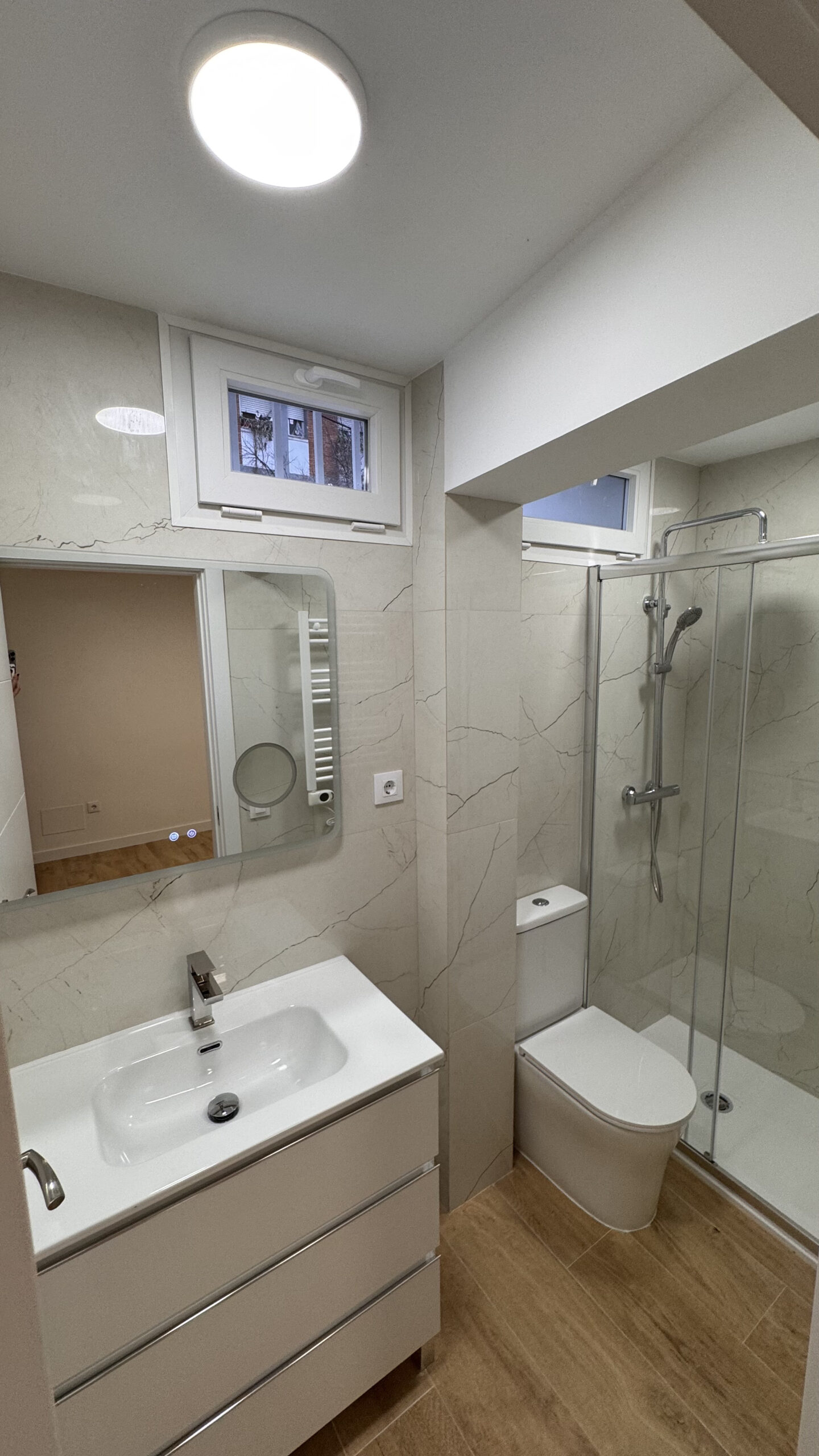 Baño modernizado con espejo con iluminación integrada con mobiliario nuevo.